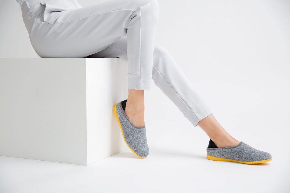 Persona con pantalones grises con zapatos planos azules y amarillos