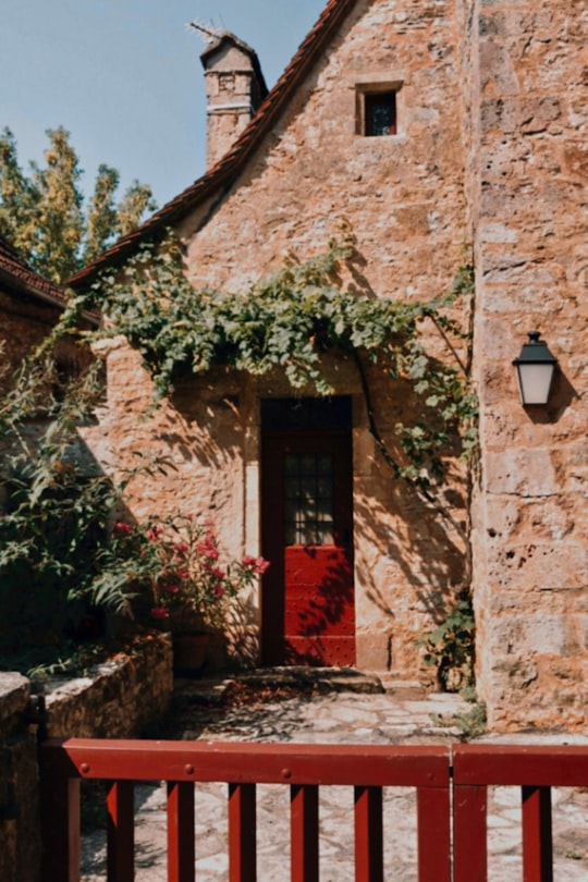 red wooden door on brown concrete building in Lot France