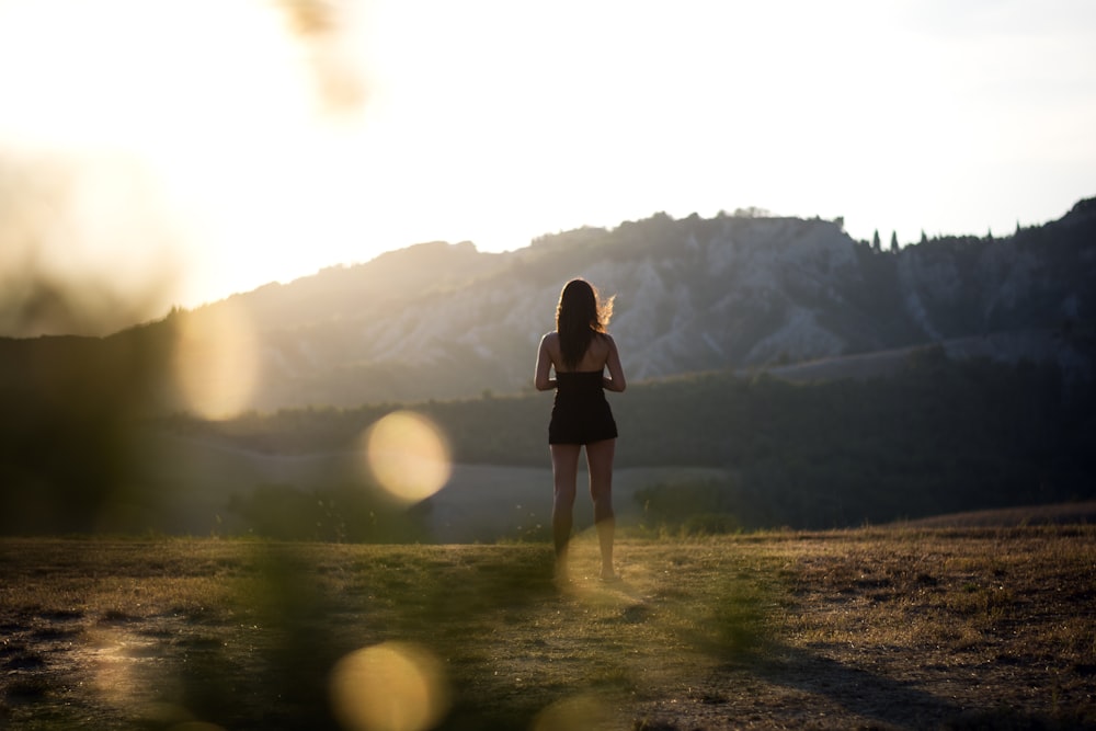 woman in black dress standing on green grass field during daytime