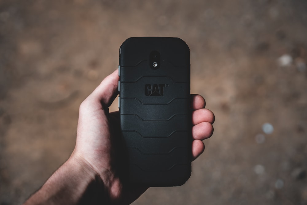 person holding black smartphone with black case