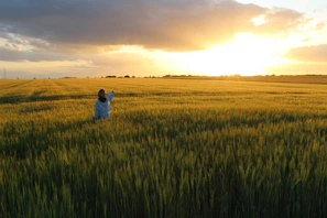 Smiling farmer standing proudly in his wheat field at sunset