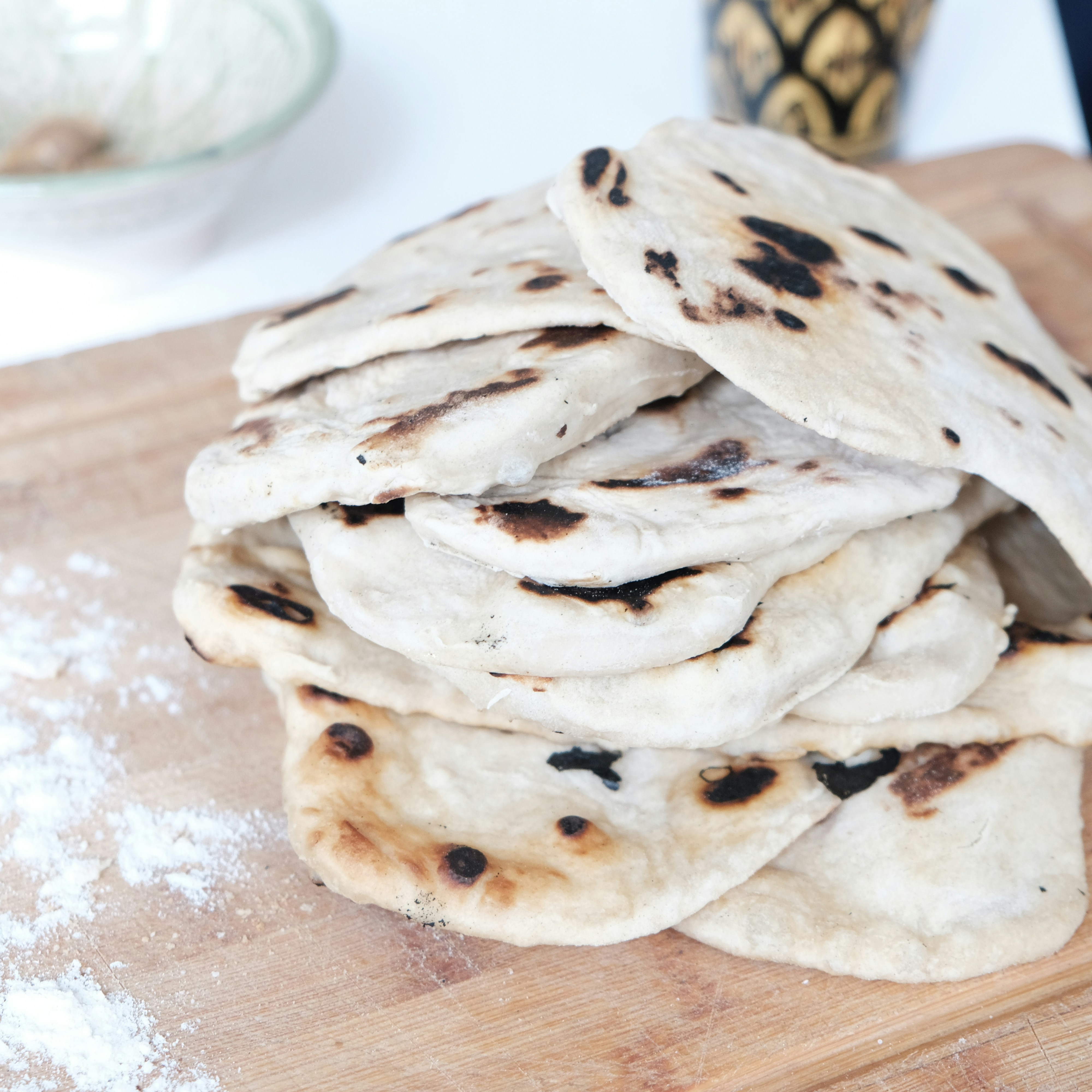 Freshly made chapati flatbreads stacked on a wooden board