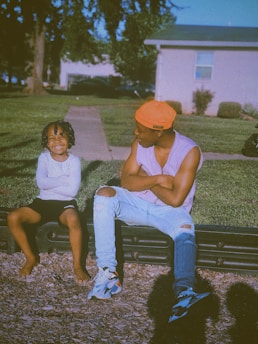A caring mentor and a smiling teenager sharing a moment outdoors in a park.