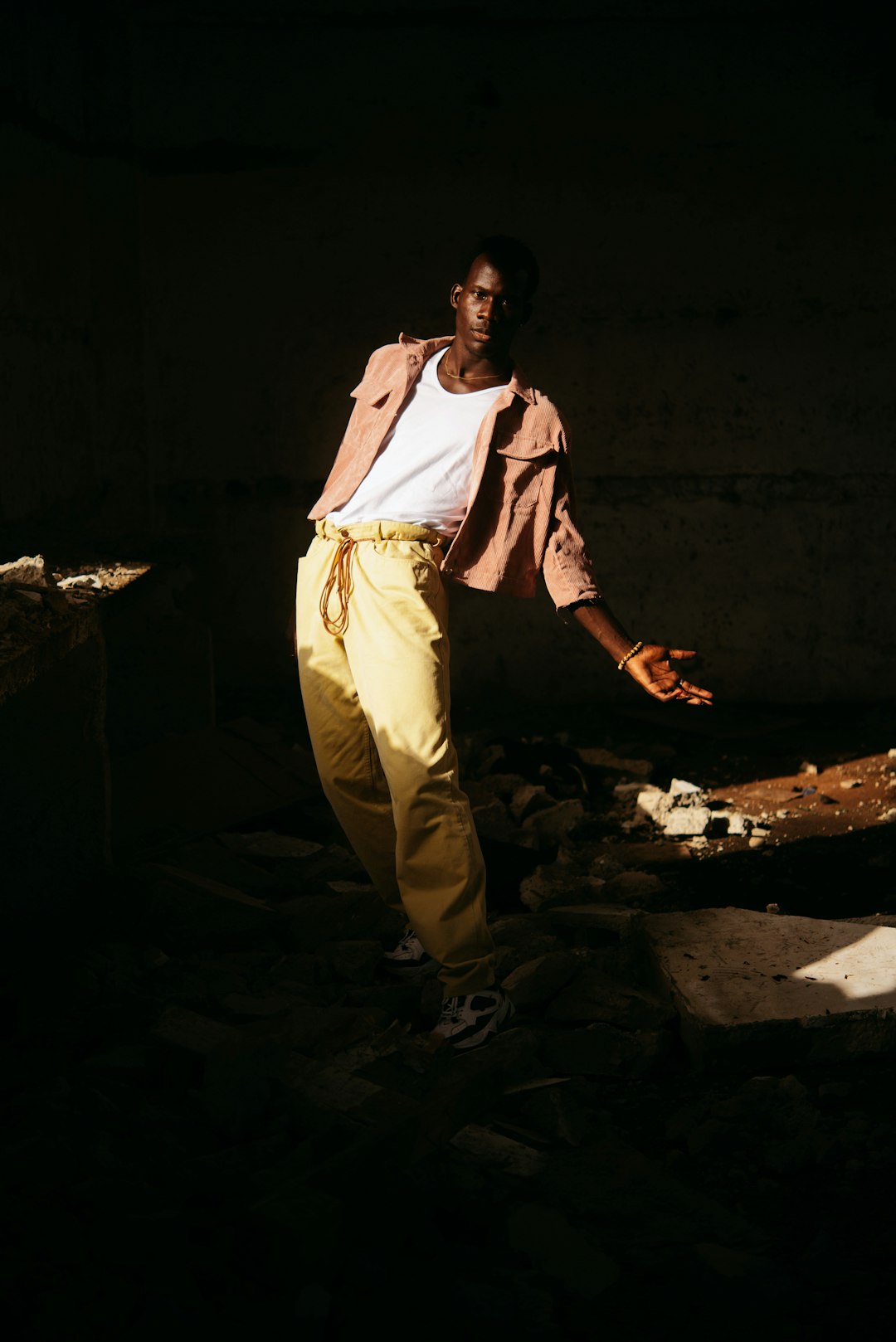 man in white long sleeve shirt and yellow pants standing on gray concrete floor