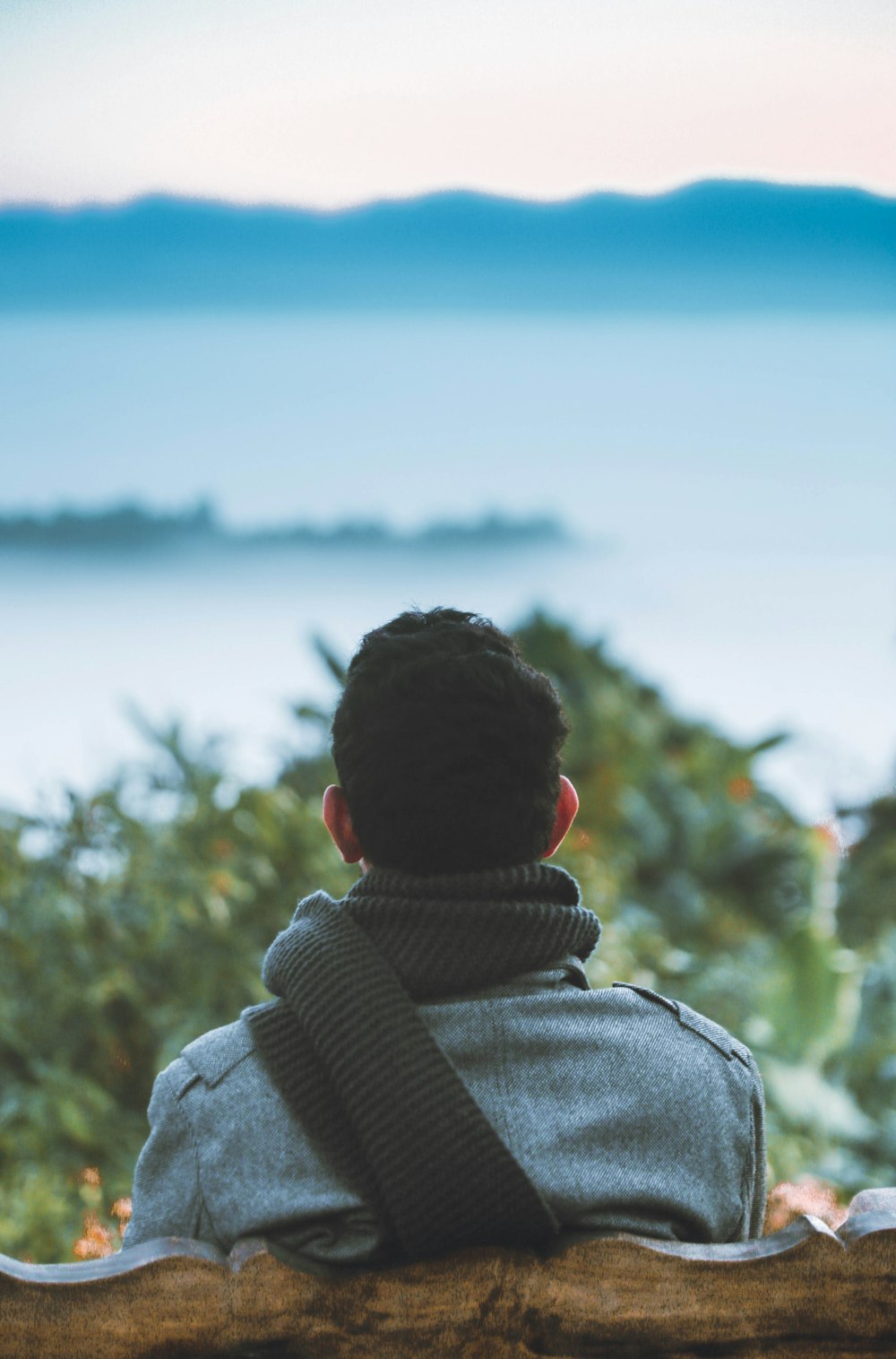 person in gray hoodie looking at blue sea during daytime