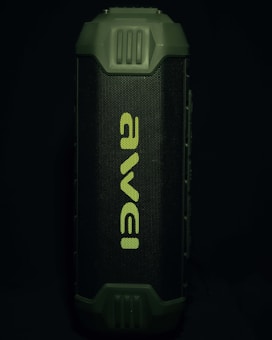 A portable speaker with a rugged, green exterior and a prominent front grille displaying the brand name in a stylized font. The design appears durable and suitable for outdoor use.