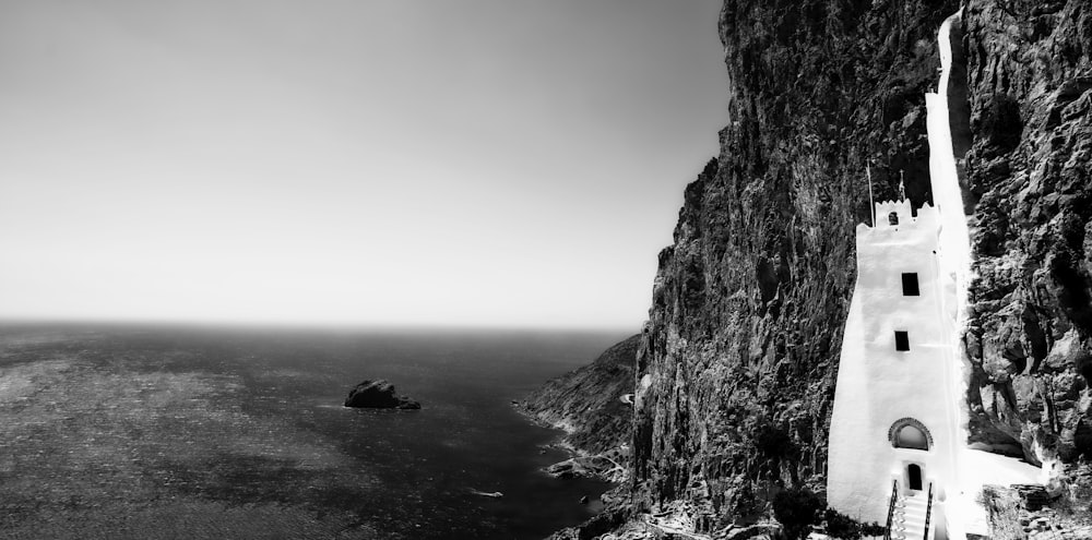 grayscale photo of rock formation near body of water