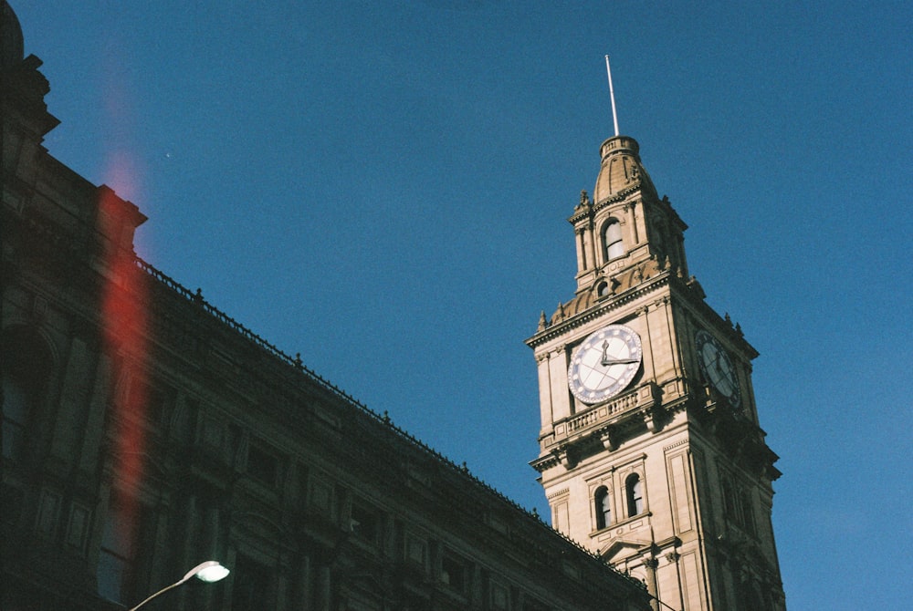 torre dell'orologio marrone e bianca sotto il cielo blu durante il giorno