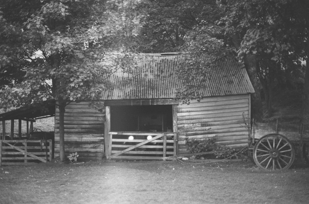 Graustufenfoto von Holzhaus in der Nähe von Bäumen