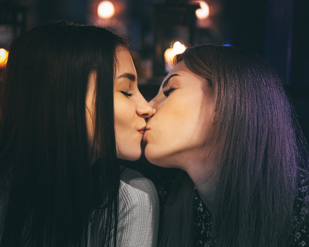 two women kissing each other in a dark room