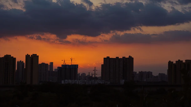 A hauntingly beautiful sunset over a deserted cityscape, with crumbling skyscrapers silhouetted against a fiery sky.