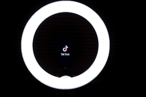 Nome e logotipo do TikTok no meio de um anel luminoso.