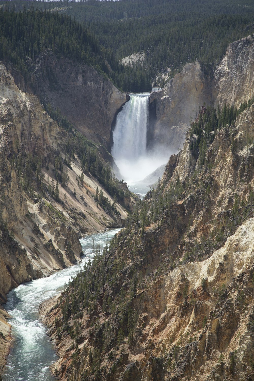 water falls between brown and gray rocky mountain