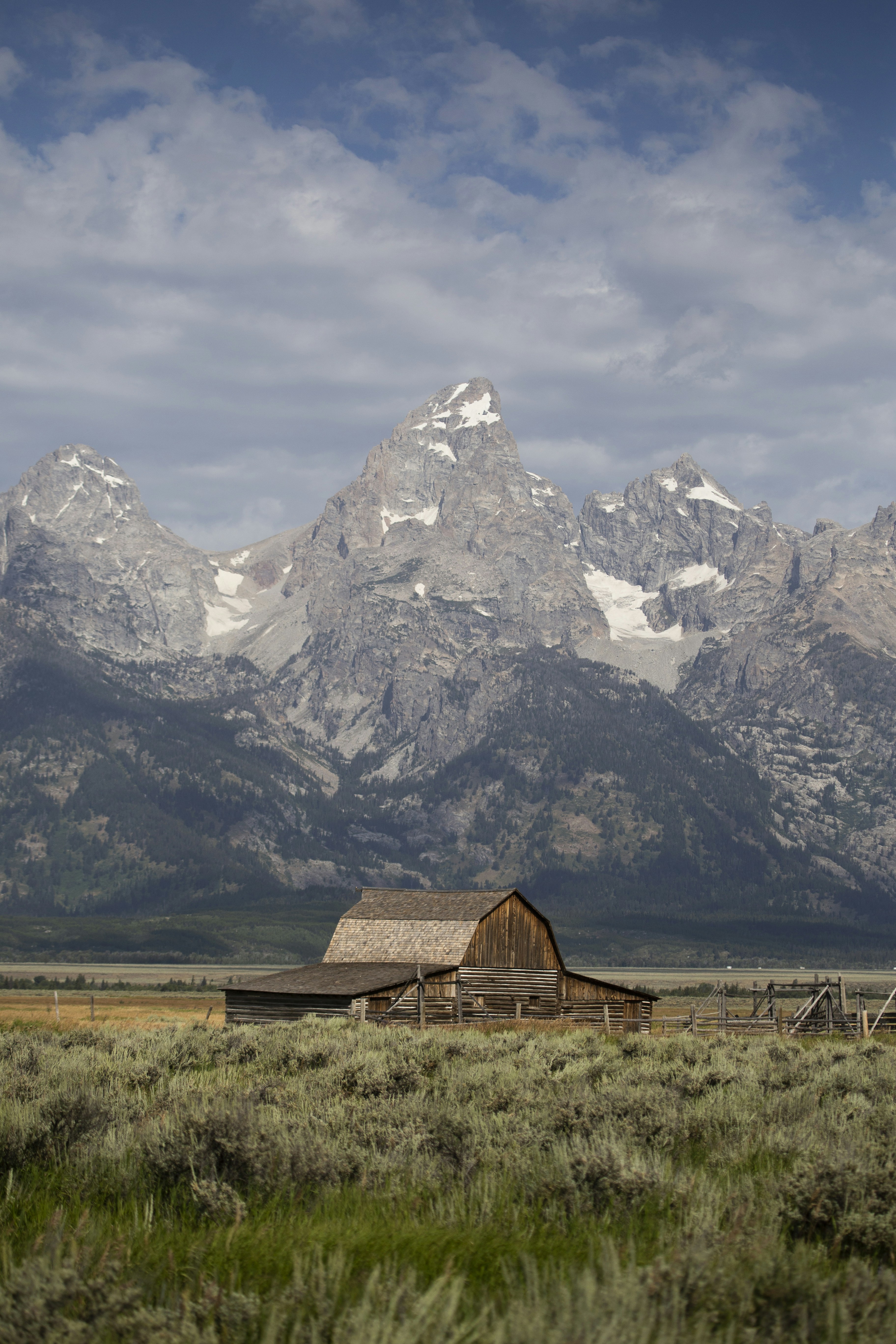 brown wooden house near snow covered mountain during daytime