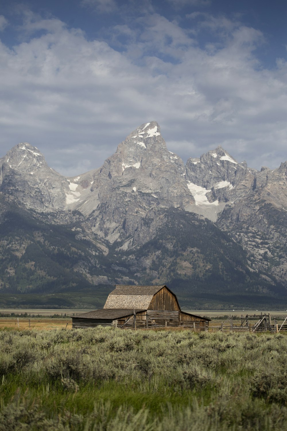 brown wooden house near snow covered mountain during daytime