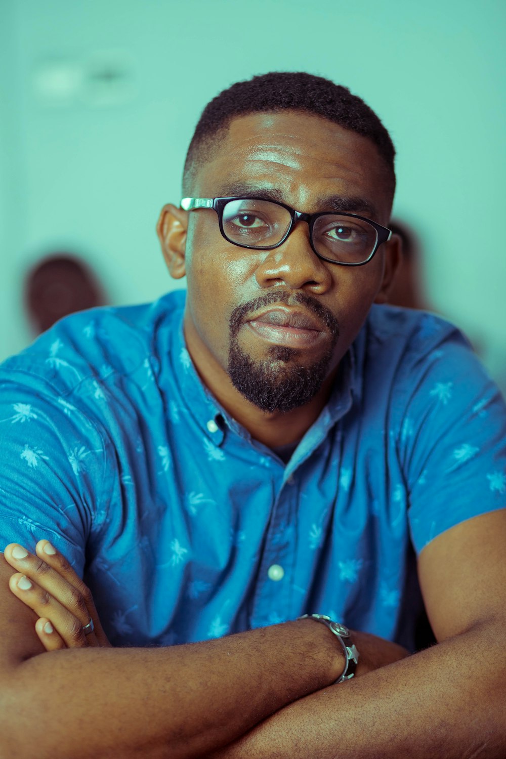 Hombre con camisa abotonada de lunares azules y blancos con gafas de montura negra