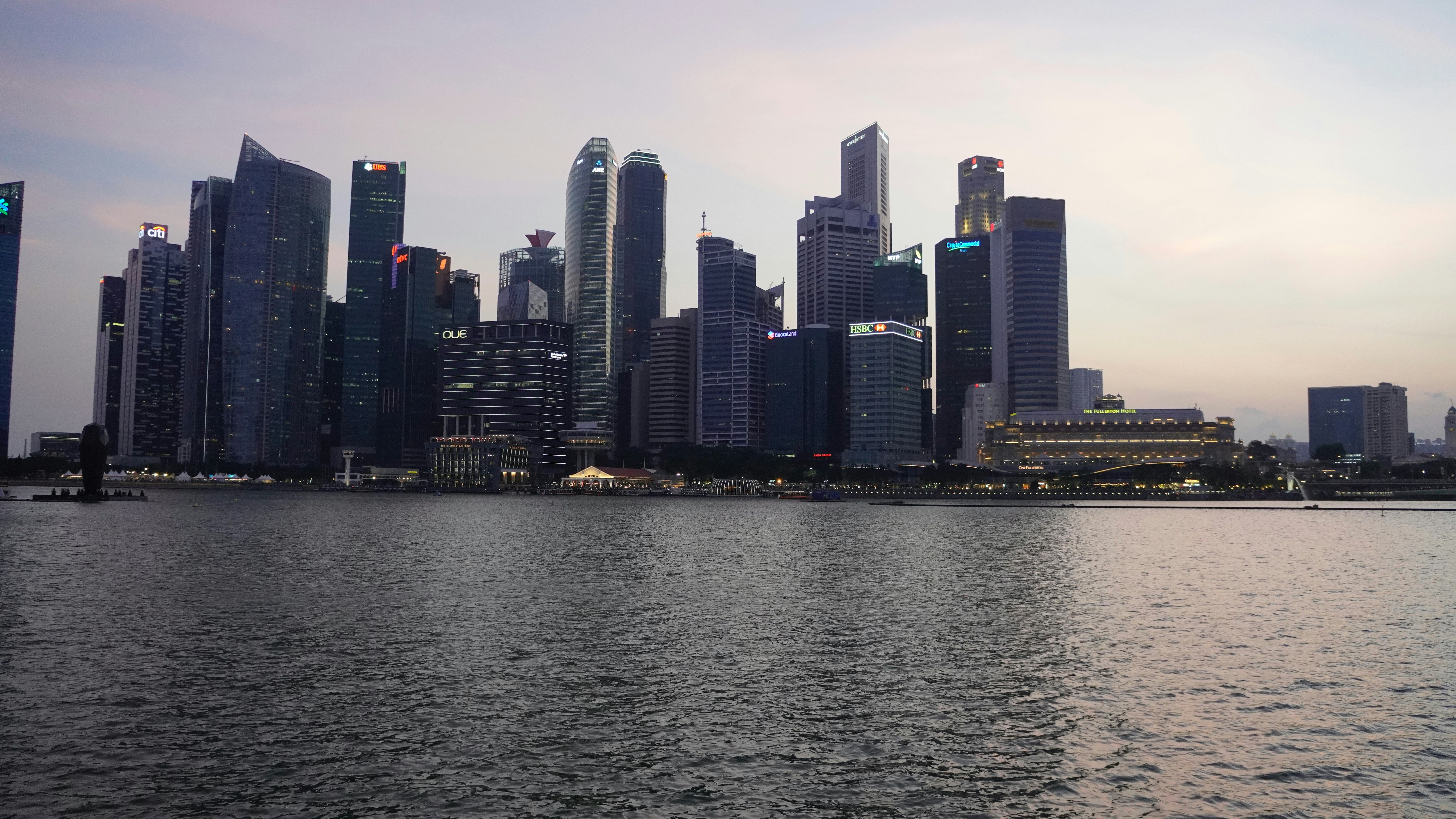Dubai skyline at dusk with illuminated skyscrapers reflecting in calm water, dark atmospheric sky