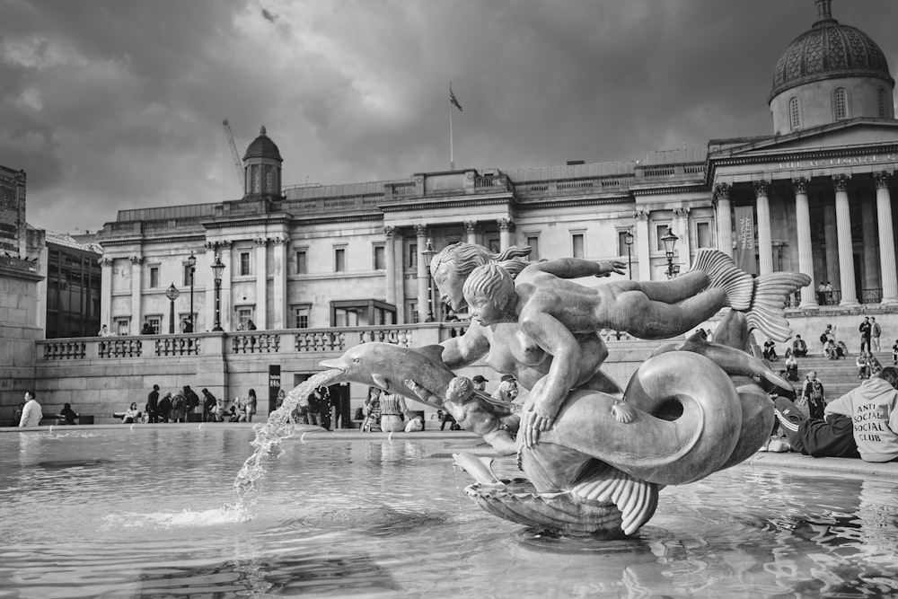 grayscale photo of fountain in front of building