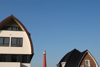 Exterior view of the crooked lighthouse vacation home with its unique tilted tower under a bright blue sky.