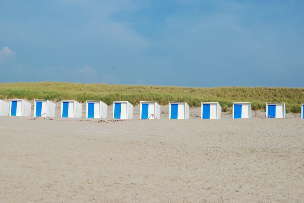 white plastic chairs on brown sand during daytime