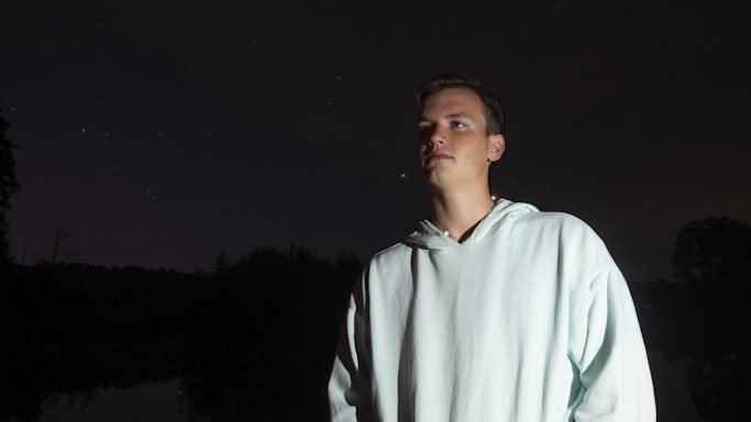 A cozy black and white hoodie hanging against a starry night sky background.