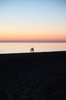 A serene beach at sunset with a couple enjoying the view, symbolizing a peaceful getaway.