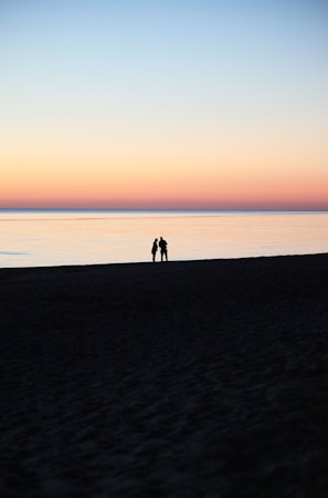 A serene beach at sunset with a couple enjoying the view, symbolizing a peaceful getaway.