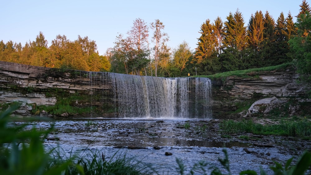 a large waterfall with a forest in the background