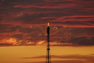 Refinery towers with pipes and flames at sunset, symbolizing petroleum products.
