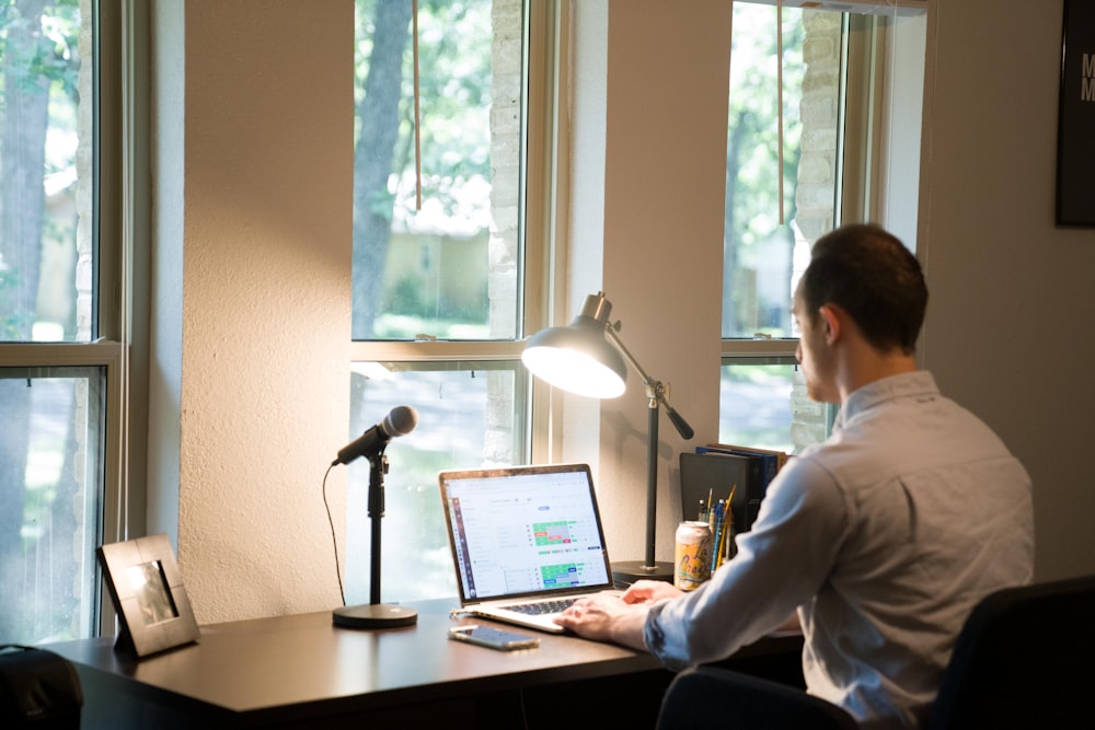 Mann im weißen Hemd sitzt auf dem Stuhl mit Laptop