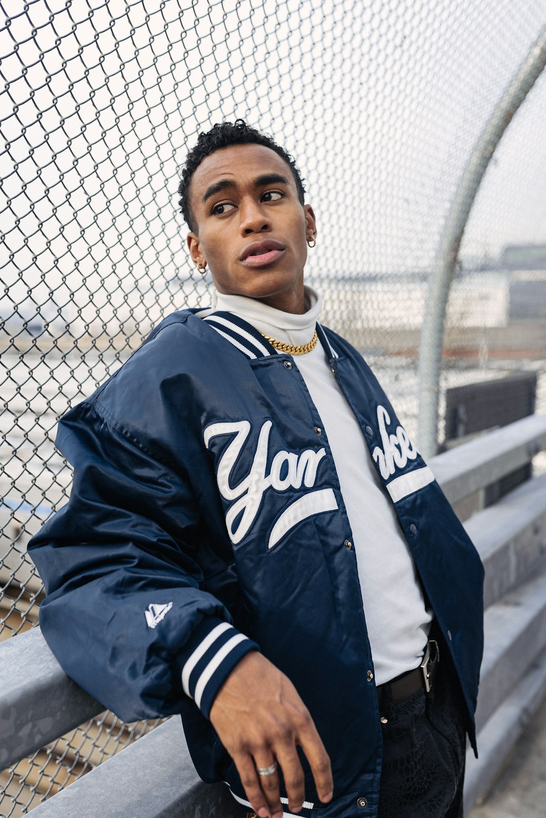 man in black and white adidas jacket standing beside chain link fence