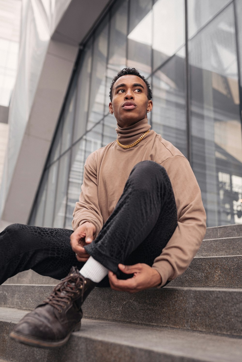 man in brown sweater and black pants sitting on concrete stairs