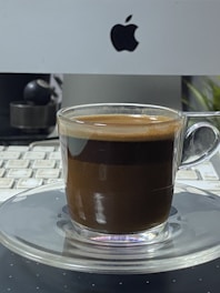 Hands typing on a keyboard with a coffee cup nearby in a bright office.