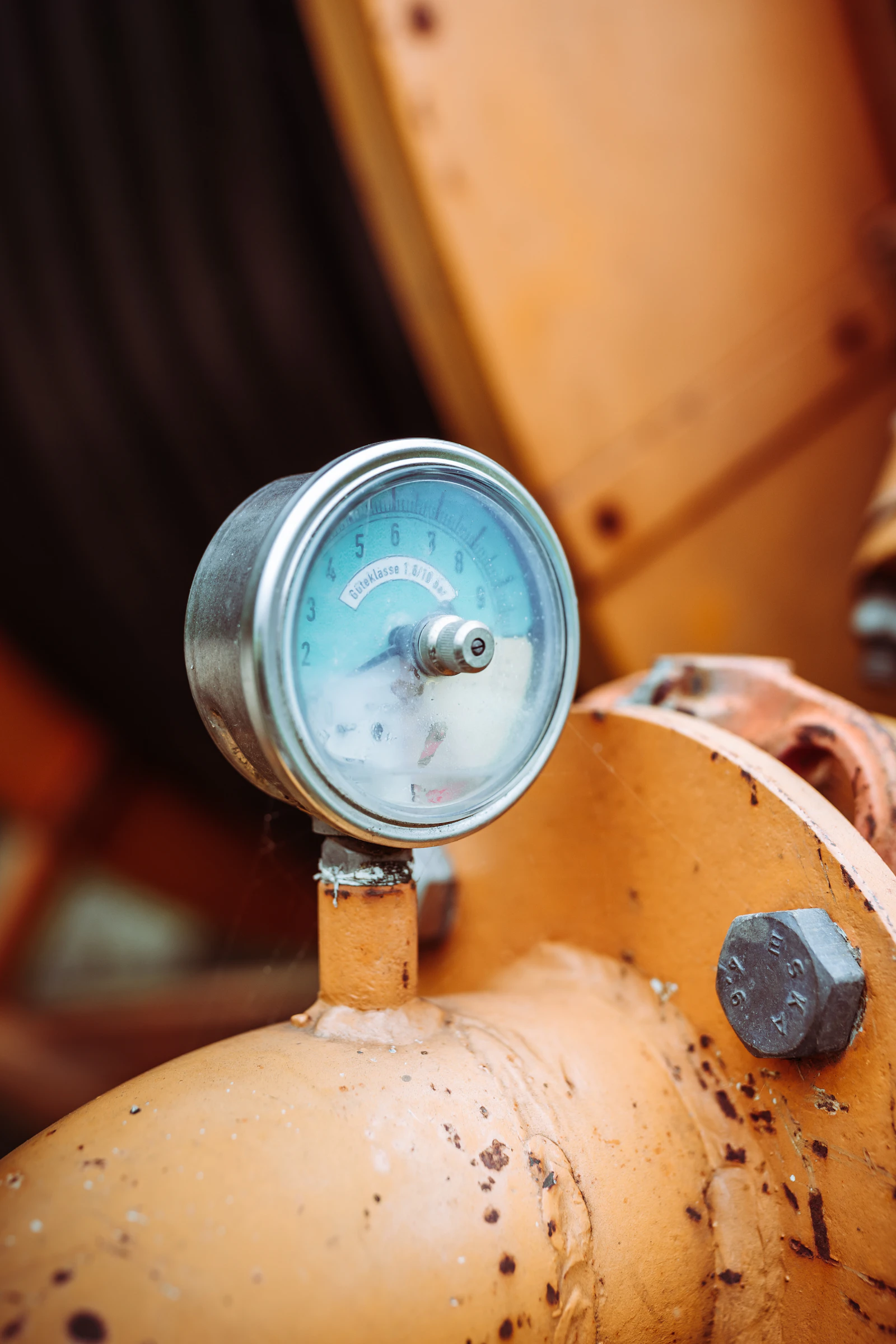 A pale blue pressure gauge mounted on an orange pipe
