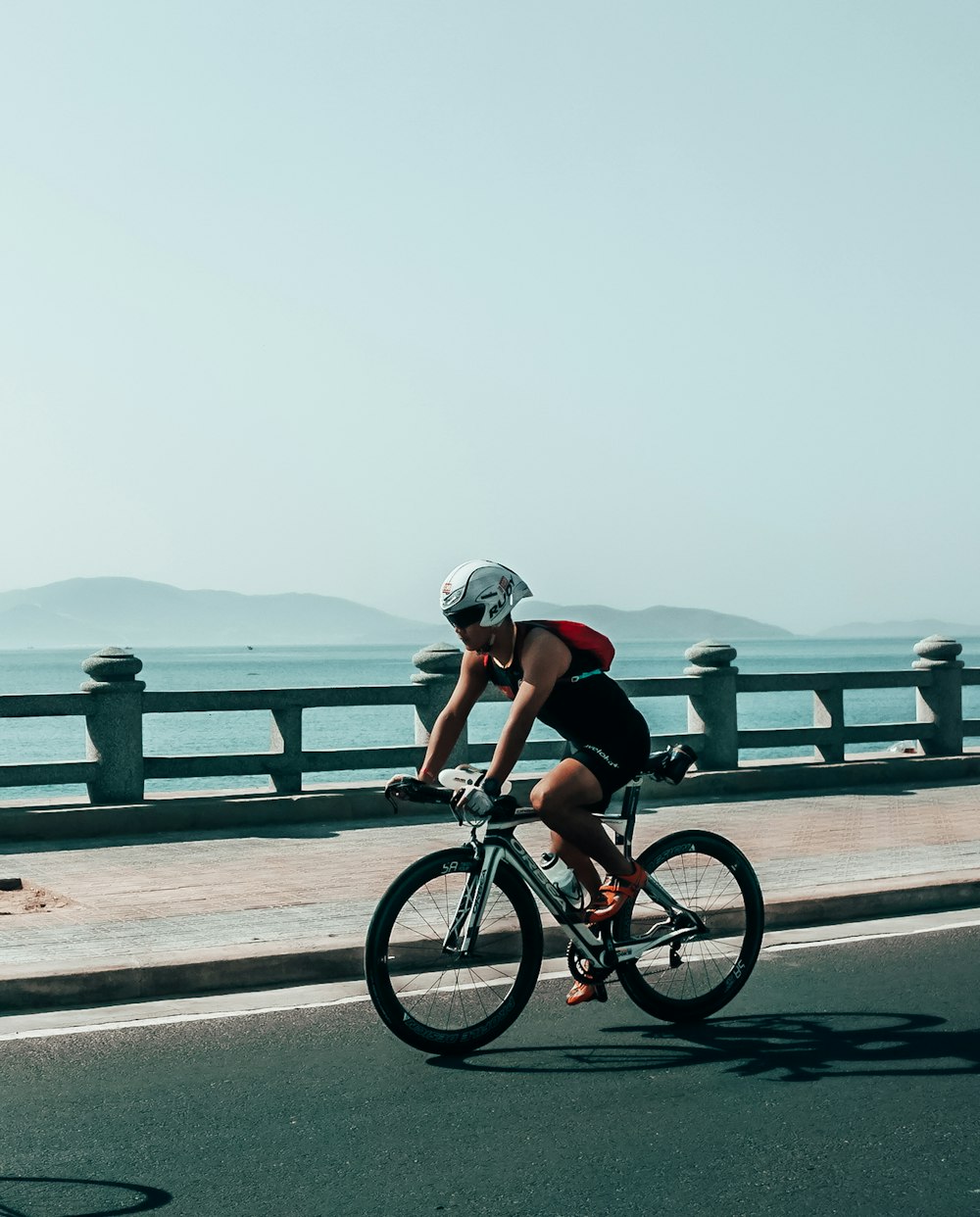 homem na camisa preta que anda de bicicleta na estrada durante o dia