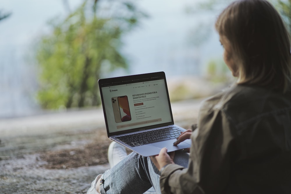 woman in brown coat using macbook air