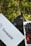 A smartphone with a visible Apple logo is placed on grass, accompanied by a blurred 'Swapc...etc' card and a box of red and black beads in the foreground.