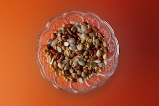 A basket filled with assorted organic nuts and seeds on a green leafy background.