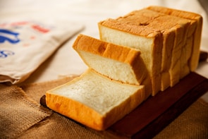Freshly baked golden-brown bread loaf cooling on a wooden board.
