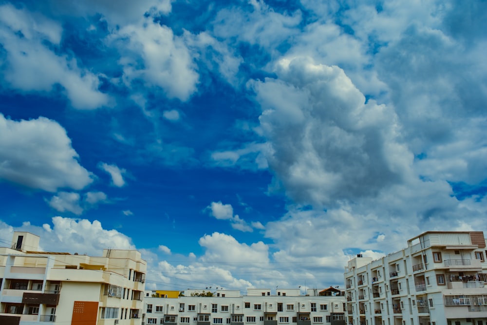 a cloudy blue sky with white buildings in the background