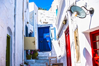 A quiet village alley in Santorini with whitewashed walls and bright blue doors glowing in the sunset.