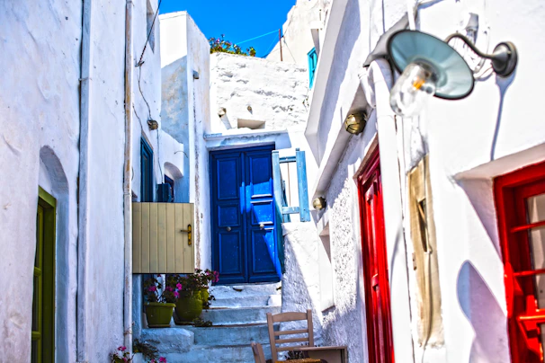 A quiet village alley in Santorini with whitewashed walls and bright blue doors glowing in the sunset.
