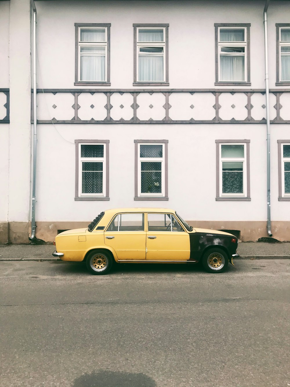 yellow and black car parked in front of white concrete building
