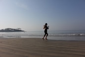 woman in black dress running on beach during daytime