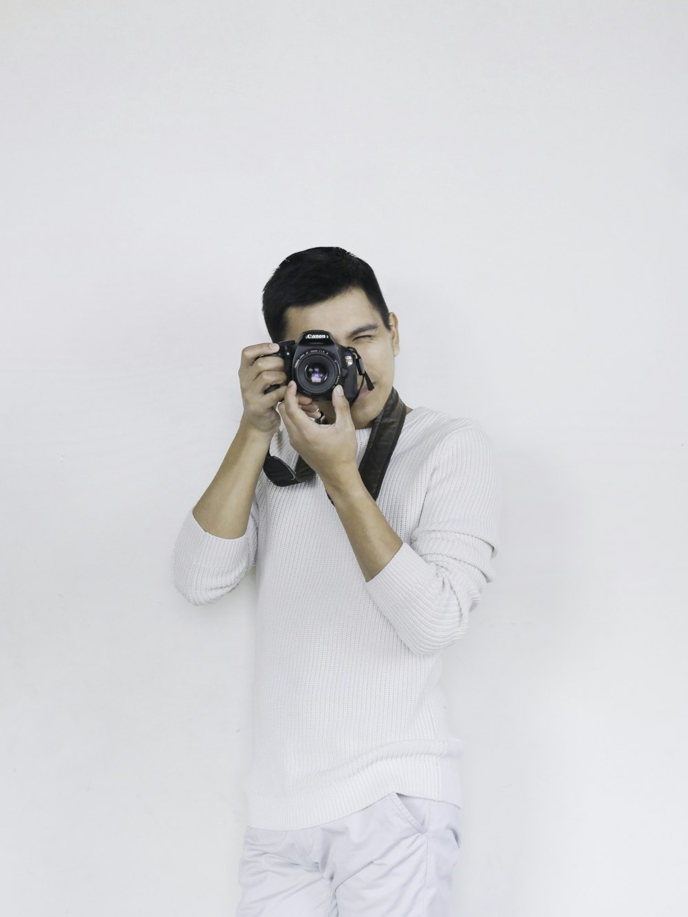 woman in white sweater holding black dslr camera