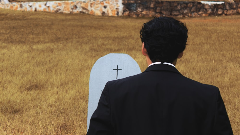 man in black suit standing on brown grass field during daytime