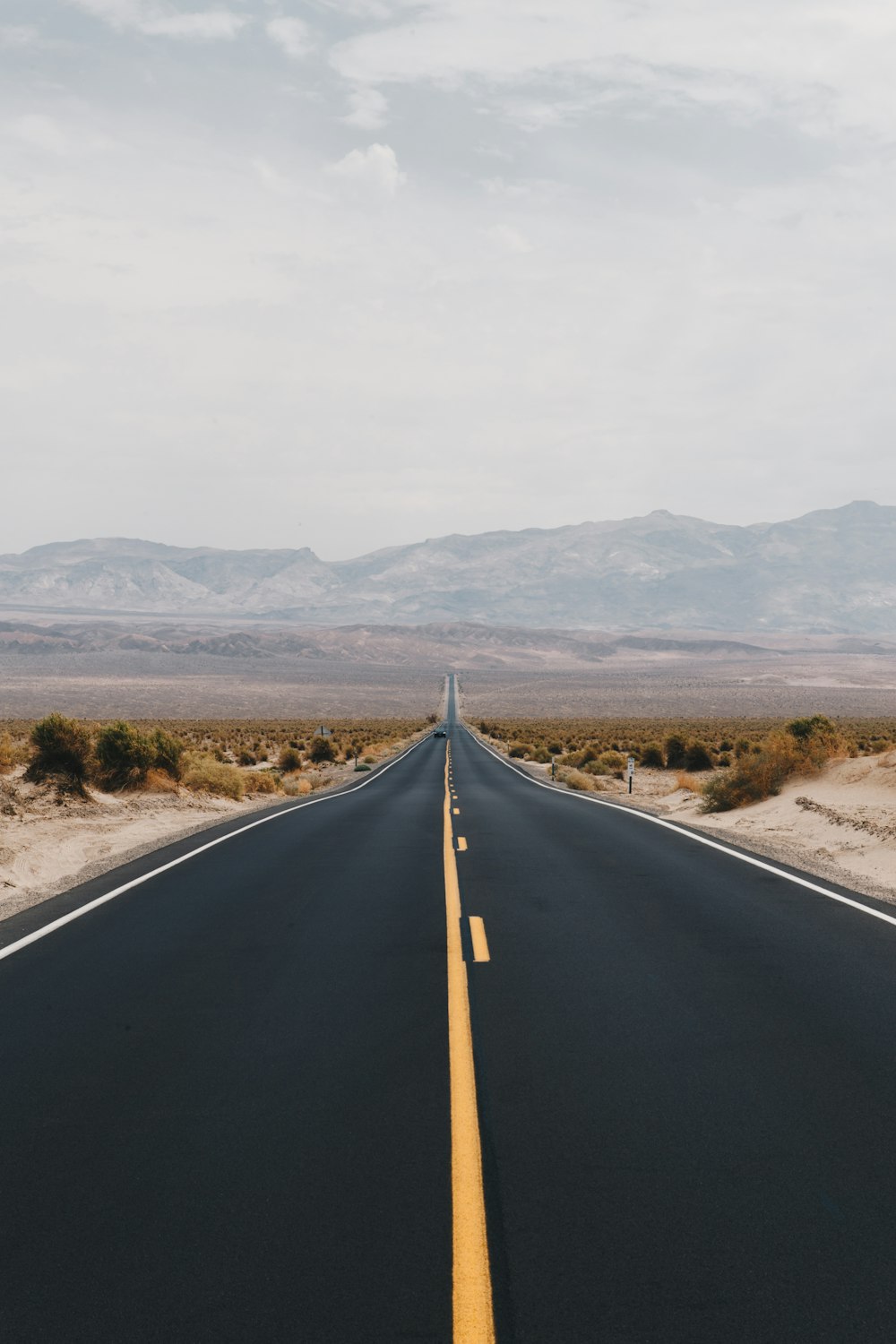 black asphalt road near brown mountains during daytime