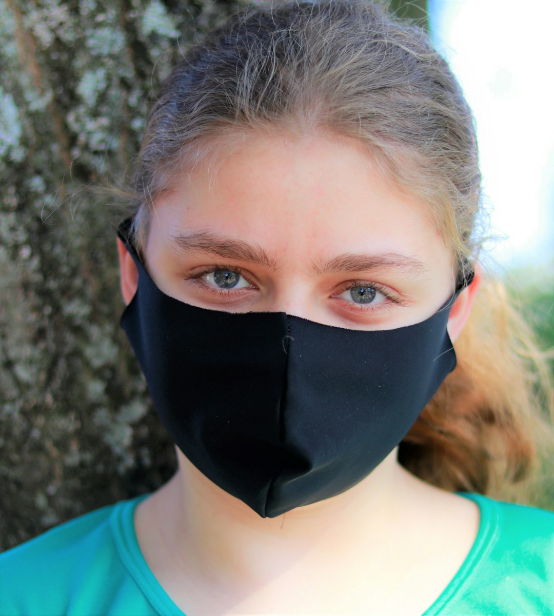 woman in green crew neck shirt wearing black mask