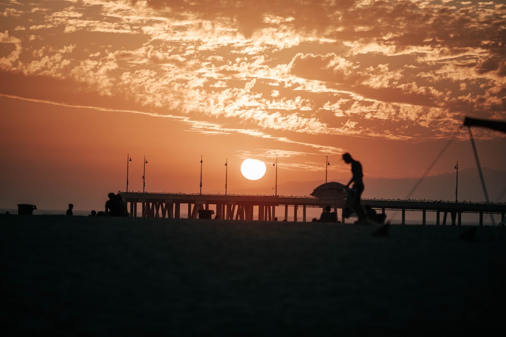 silueta del hombre y de la mujer que caminan en la playa durante la puesta del sol