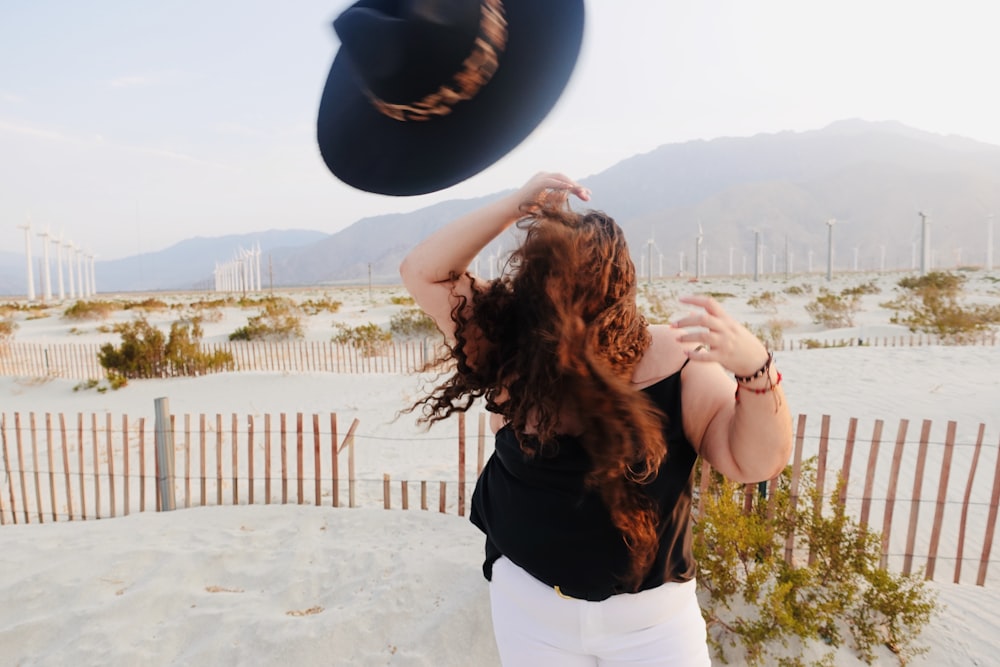 woman in black shirt and white pants holding blue hat